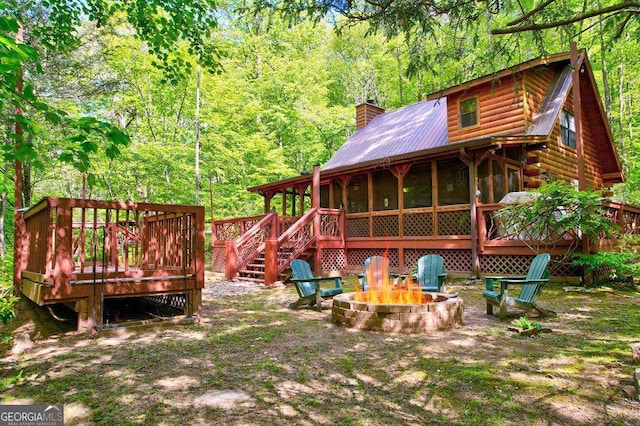 369 Trillium Rd, Suches, GA 30572 - rear view of house with a sunroom, a fire pit, a chimney, metal roof, and a wooden deck