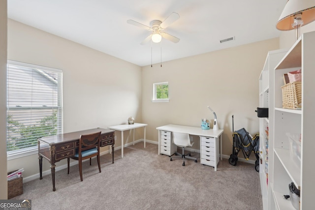 carpeted office space featuring a ceiling fan and baseboards