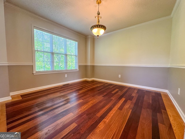 spare room with a textured ceiling, crown molding, wood finished floors, and baseboards