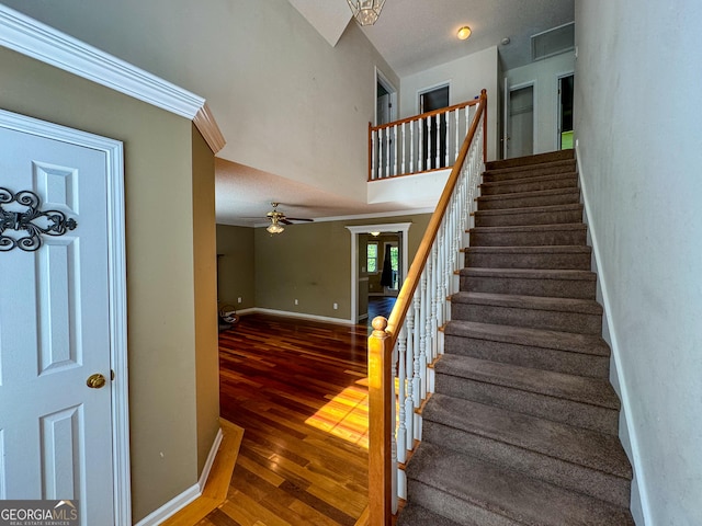 stairs featuring wood finished floors, baseboards, and ceiling fan