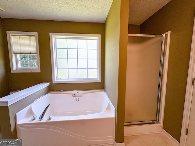 bathroom with a shower stall, a bath, and a textured ceiling