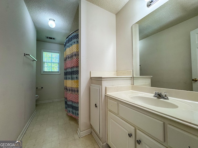 bathroom featuring a textured ceiling, toilet, baseboards, vanity, and tile patterned floors