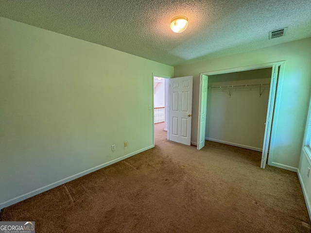 unfurnished bedroom featuring carpet flooring, baseboards, a textured ceiling, and a closet