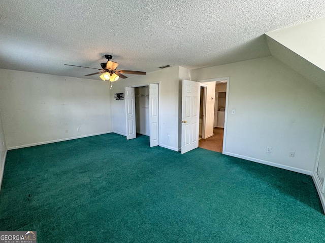 unfurnished bedroom with a textured ceiling, dark colored carpet, a closet, a ceiling fan, and baseboards