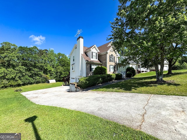 view of side of home with driveway, a yard, and a chimney