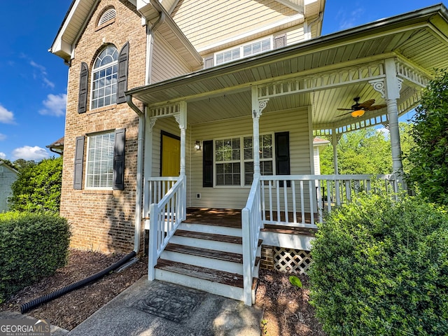 entrance to property with ceiling fan, brick siding, and covered porch