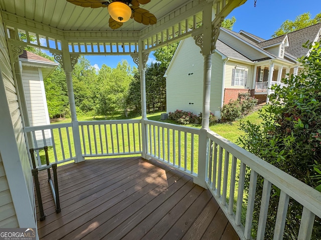 wooden deck with ceiling fan and a lawn
