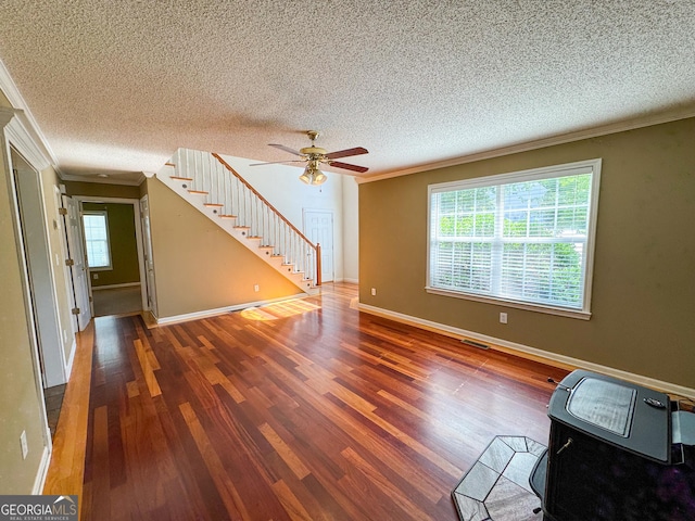 unfurnished living room with stairs, ornamental molding, wood finished floors, ceiling fan, and a textured ceiling