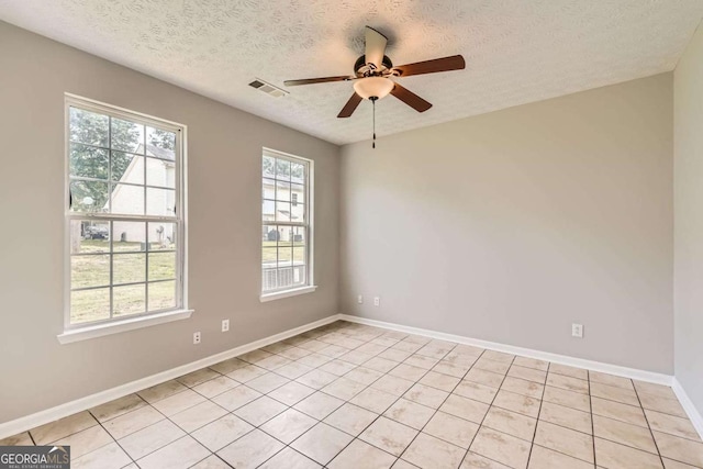 empty room featuring a textured ceiling, a ceiling fan, light tile patterned floors, and baseboards