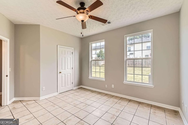 unfurnished bedroom featuring a textured ceiling, light tile patterned floors, baseboards, and ceiling fan