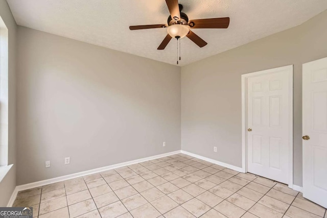 spare room with a ceiling fan, light tile patterned floors, and baseboards