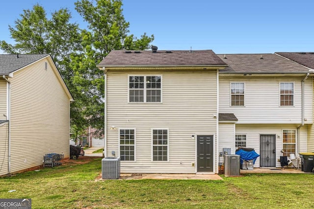 back of house with central AC unit and a lawn