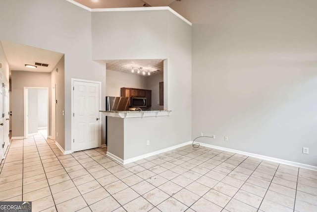 spare room featuring baseboards, a high ceiling, and light tile patterned flooring