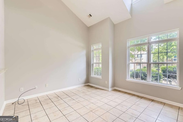 spare room with light tile patterned floors, high vaulted ceiling, and baseboards