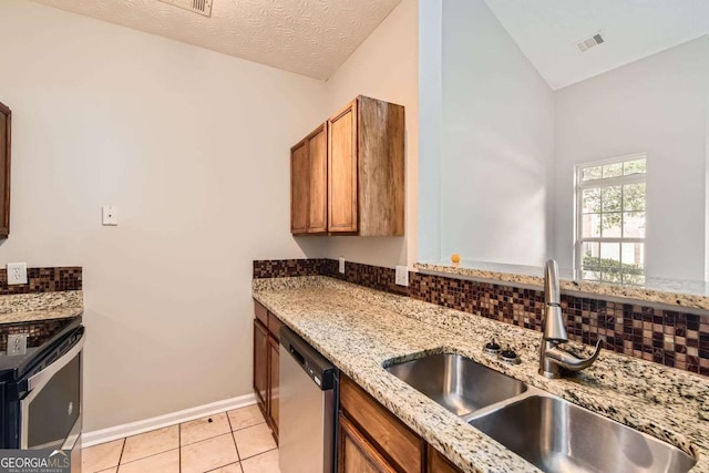 kitchen featuring a sink, stainless steel appliances, brown cabinets, lofted ceiling, and light tile patterned floors