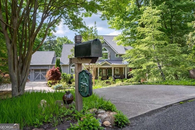 view of front of home with driveway, a chimney, and roof with shingles