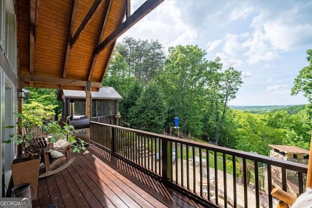 wooden terrace with a grill and a forest view
