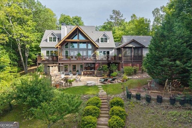 back of house featuring a patio, a wooden deck, a chimney, and a sunroom