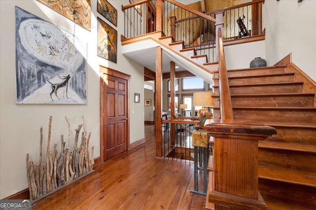 entryway featuring hardwood / wood-style floors, a high ceiling, baseboards, and stairs