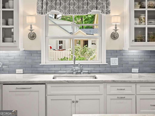 kitchen featuring a sink, white cabinets, and glass insert cabinets