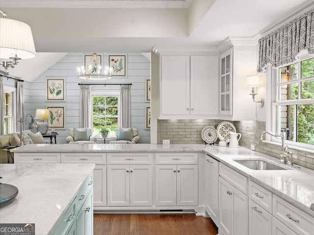 kitchen featuring a chandelier, a sink, healthy amount of natural light, white cabinetry, and crown molding