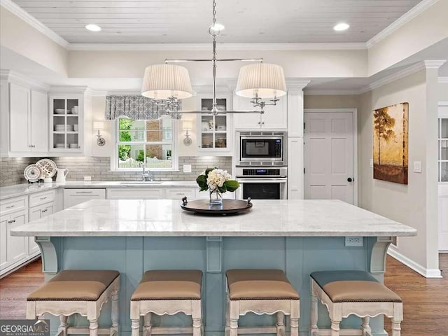 kitchen with stainless steel appliances, white cabinetry, dark wood-style floors, a breakfast bar, and recessed lighting