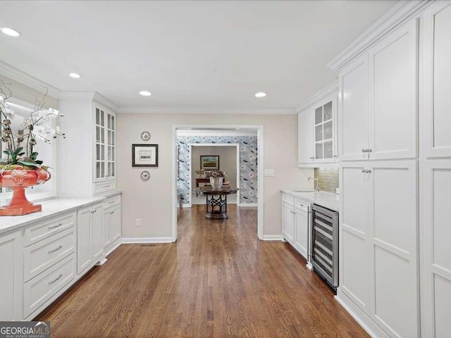 indoor dry bar featuring wine cooler, dark wood-style flooring, baseboards, ornamental molding, and recessed lighting