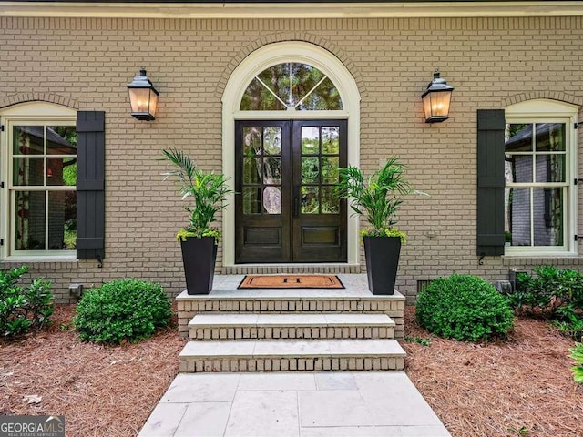 entrance to property featuring french doors and brick siding