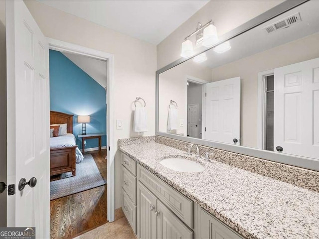 ensuite bathroom featuring vanity, wood finished floors, and baseboards