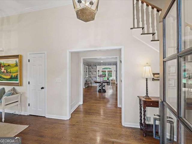 foyer featuring wood finished floors, baseboards, stairway, and a high ceiling