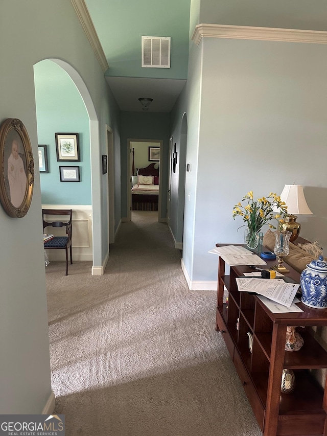 corridor with arched walkways, carpet flooring, ornamental molding, and baseboards