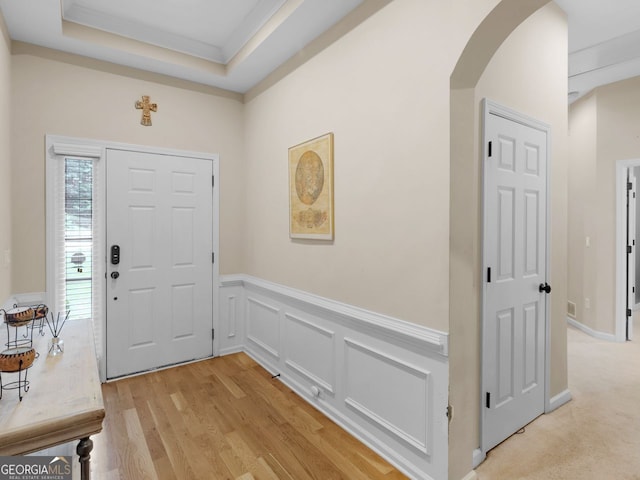 361 Brackin Trce, Grayson, GA 30017 - entryway featuring arched walkways, a wainscoted wall, light wood finished floors, a decorative wall, and a tray ceiling