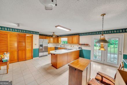 111 Roberson St, Dublin, GA 31021 - kitchen with stainless steel fridge with ice dispenser, light countertops, a textured ceiling, pendant lighting, and a center island