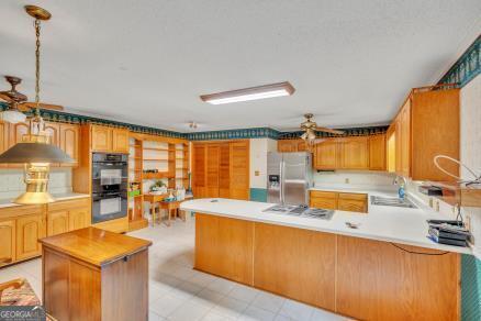 111 Roberson St, Dublin, GA 31021 - kitchen with stainless steel refrigerator with ice dispenser, a sink, white gas stovetop, a peninsula, and light countertops