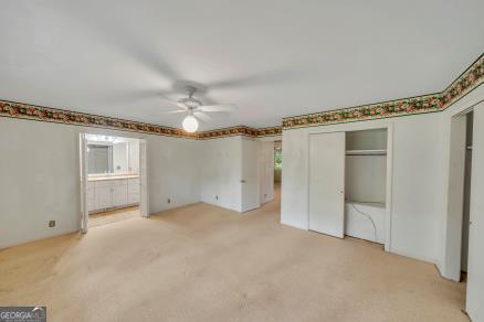 111 Roberson St, Dublin, GA 31021 - unfurnished bedroom featuring light colored carpet, connected bathroom, and a ceiling fan