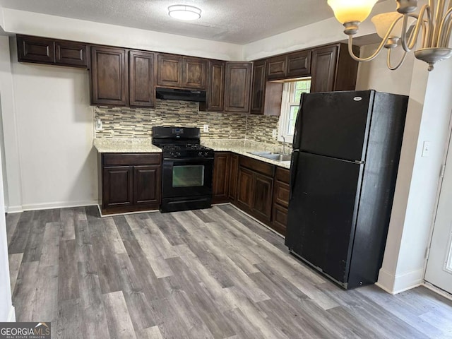 5460 Huron Dr, Morrow, GA 30260 - kitchen with black appliances, under cabinet range hood, light countertops, a sink, and dark brown cabinetry