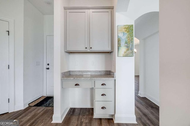 unfurnished office featuring dark wood finished floors and baseboards