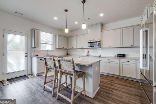 kitchen featuring appliances with stainless steel finishes, a center island, tasteful backsplash, dark wood-style flooring, and recessed lighting