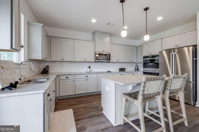 kitchen featuring stainless steel appliances, a sink, dark wood finished floors, tasteful backsplash, and recessed lighting