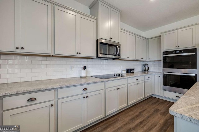 kitchen with stainless steel appliances, dark wood finished floors, tasteful backsplash, and light stone countertops