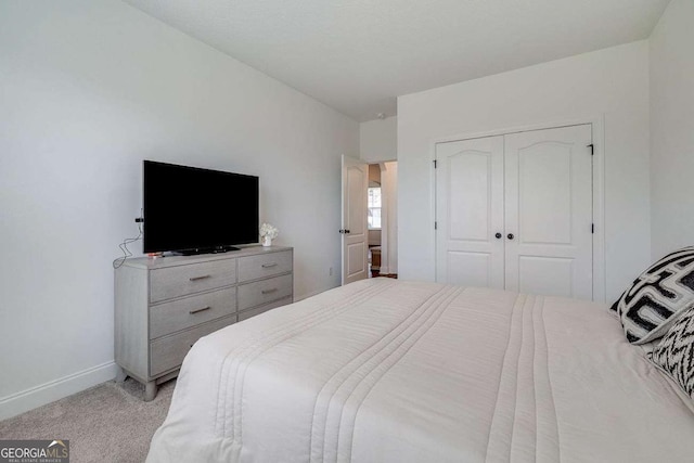 bedroom with light carpet, a closet, and baseboards