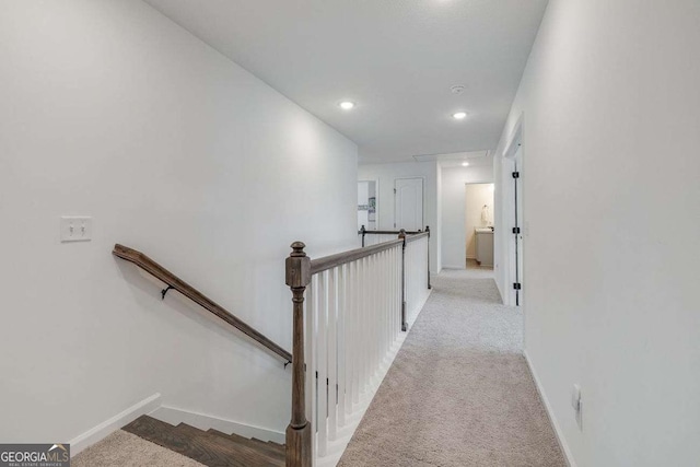 hallway featuring an upstairs landing, carpet floors, baseboards, and recessed lighting