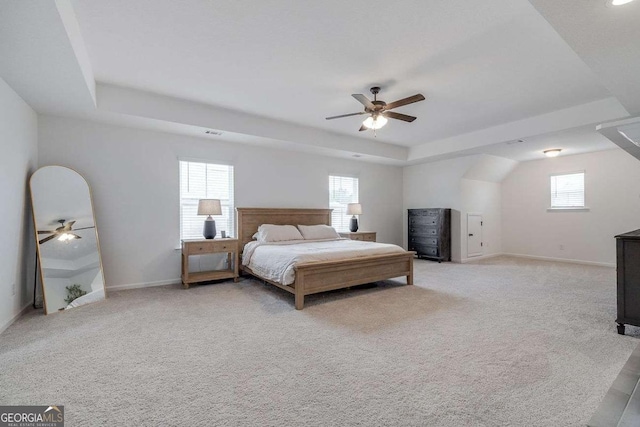 bedroom featuring a raised ceiling, baseboards, and light colored carpet