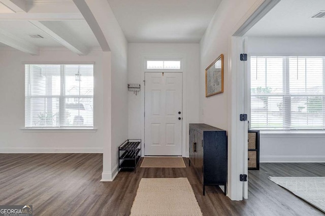 entrance foyer featuring dark wood finished floors, arched walkways, baseboards, and beamed ceiling