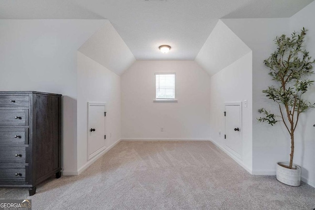 additional living space featuring light carpet, vaulted ceiling, and baseboards