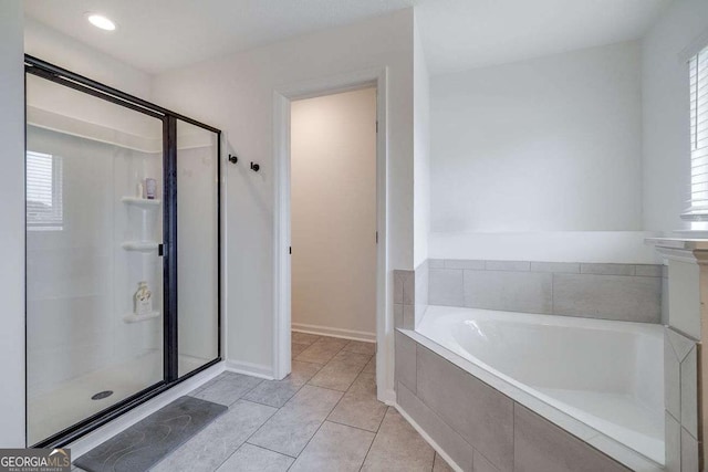 full bathroom featuring a shower stall, a garden tub, plenty of natural light, and baseboards