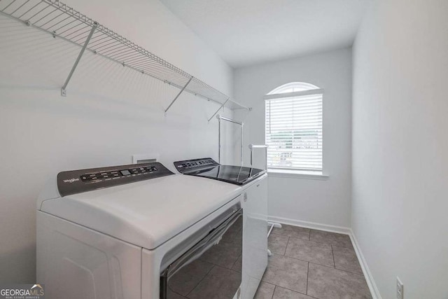 clothes washing area with washing machine and clothes dryer, baseboards, and light tile patterned floors