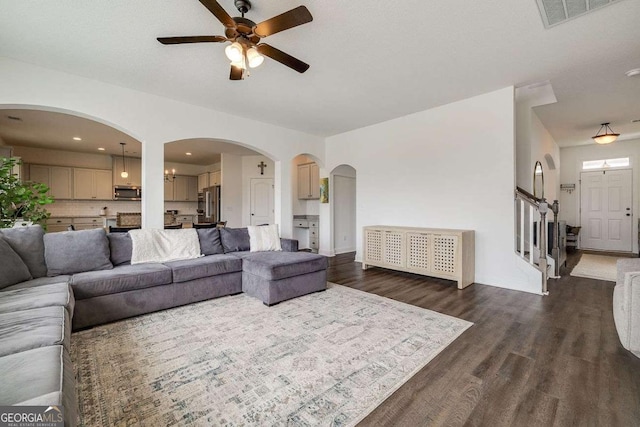 living area with ceiling fan, dark wood-type flooring, stairway, and baseboards