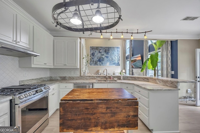 kitchen featuring appliances with stainless steel finishes, a sink, light wood-type flooring, white cabinetry, and crown molding