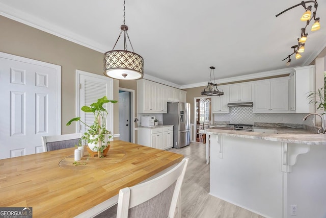 kitchen with stainless steel refrigerator with ice dispenser, a peninsula, white cabinetry, decorative backsplash, and light wood finished floors